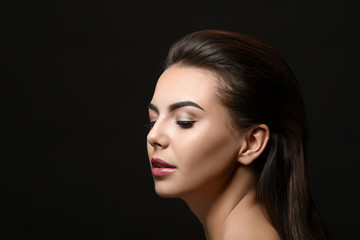 Young woman with beautiful eyebrows on black background