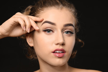 Fototapeta na wymiar Young woman with beautiful eyebrows on dark background