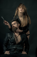 Barber concept. Couple of sexy girl and brutal bearded hipster with mustache, black background. Hipster with beard and sexy girl holds straight razor. Barber with straight razor works on haircut