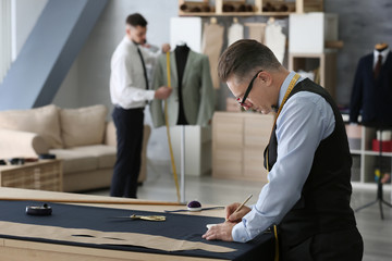 Mature tailor and his assistant working in atelier
