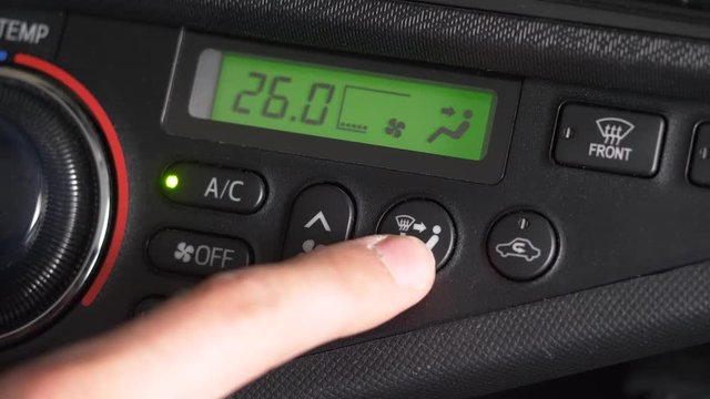 Turning the AC on by adjusting the climate control buttons and knobs on a car.