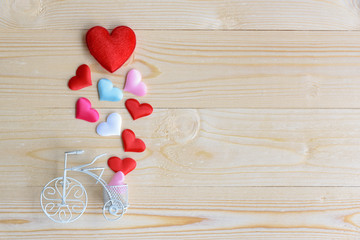 Valentine's day / special occasion concept : Top / overhead view of big red velvet heart with small pink, white and sky blue hearts on rustic wood texture background, copy space. A bike on wood floor.