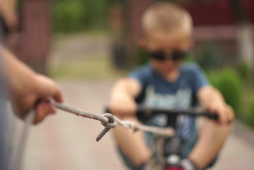  little boy pulls a rope bike with little boy blurred focus       