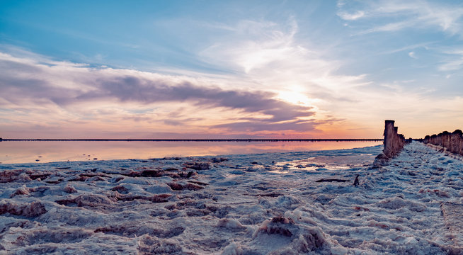 Beautiful sunset or sunrise over a salty lake, Wooden hemp in the build-up of salt after the drying of the lake