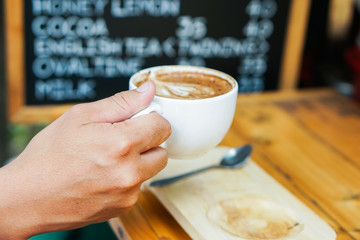 Man hand holding a Latte Art coffee mug.