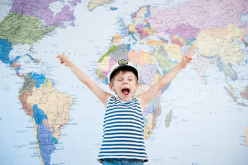 Obraz premium happy shouting little kid in captain hat and striped shirt world map background