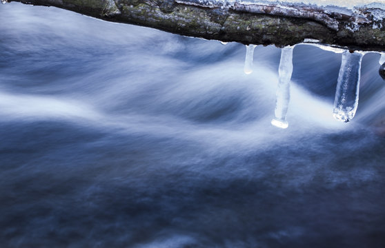 Abstract shot wintertime about some icicles in front of a cold stream, long exposure. Domorkapu, Hungary