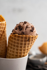 Homemade chocolate ice cream in waffle cones and pieces of dark chocolate 