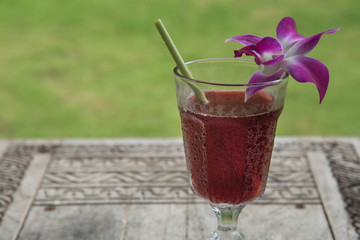Juice with orchid flowers placed above the glass.