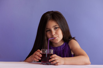 Cute little brunette girl drinking fresh juice