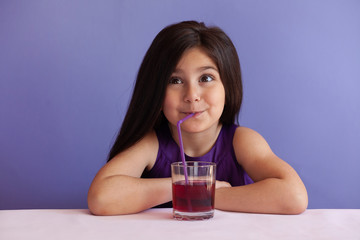 Cute little brunette girl drinking fresh juice