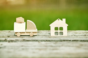 Wooden model of cargo truck delivering box to house. Shipping and transportation concept