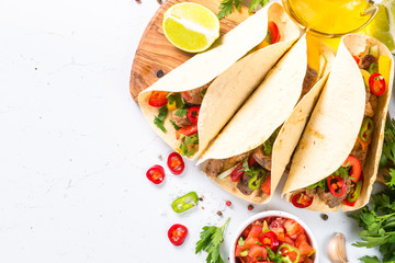 Mexican pork tacos with vegetables and salsa on white.