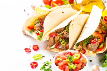 Mexican pork tacos with vegetables and salsa on white.