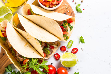 Mexican pork tacos with vegetables and salsa on white.
