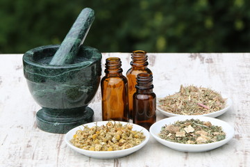 Herbal medicine, Getrocknete Kräuter für Gesundheitstees, Kamillenblüten, Weidenröschen und Teemischung neben Medizinflaschen und einem Mörser