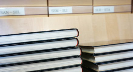 Fototapeta premium Book with black cover stacked, old library catalog blurred in the background