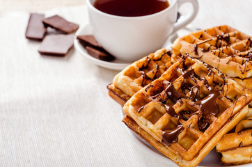 Belgian waffles on a plate with chocolate for breakfast on a napkin. Fast snack.