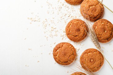 Oatmeal cookies with oat flakes and spikelets on a white wooden background. Copy space, top view.