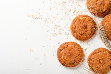 Oatmeal cookies with oat flakes and spikelets on a white wooden background. Copy space, top view.