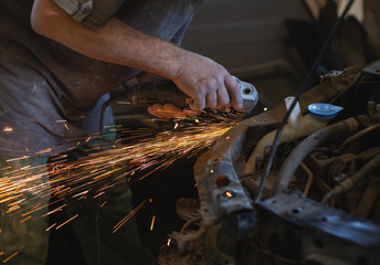 The Employee of The Car Service Station Produces Body Repair with a Welding Machine in Hand. Sparks From Welding Machine.