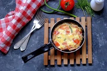 Lush omelette or frittata with garlic arrows and tomatoes in a portioned pan