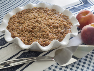 Whole pie with streusel topping accompanied with peaches