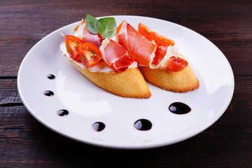 Italian bruschetta with Prosciutto di Parma and cream cheese on rustic background. Delicious snack,...