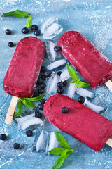 Blueberry ice cream on a stick with a blackberry. Cold berries sorbet with ice.