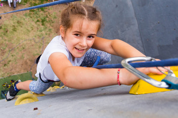 Beautiful young girl climbing to big artificial wall