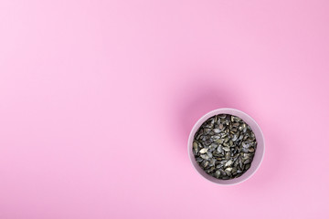 Raw pumpkin seeds on the pink  background.Trendy Bright Colors. Concept. Minimalism. Healthy Food. Diet Nutrition.Top View. Flat Lay. Copy space for Text.