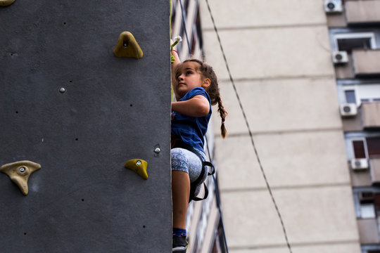 Beautiful Young Girl Climbing To Big Artificial Wall