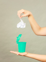 Woman putting paper into small trash can