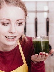 Woman in kitchen holding vegetable smoothie juice