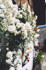 white bushy braided roses in garden on background of stone old house closeup on a sunny summer day, buds of delicate flowers for postcards, color bloom in garden, beautiful blossom in outdoor street