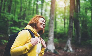 smiling tourist traveler with backpack into road at summer green forest, view back girl hiker in...