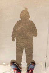 boy`s reflection on a puddle of water using his feet as silhouette feet