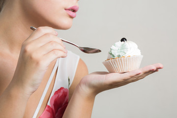 Attractive blonde woman eating tasty sweet dessert with butter cream