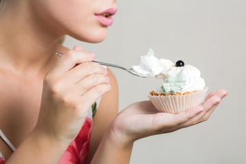 Closeup shot of young blonde model eating tasty sweet dessert with butter cream