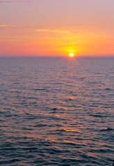 Fototapeta premium Sunset over the sea. Reflection of sunlight in the sea waves. Red sky in the rays of the sunset.