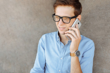 Beautiful stylish business guy with glasses, posing on the beach, hipster talking on the phone, work on vacation, for advertising, text insertion