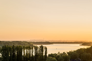 early morning on the river bank. view of the river with a small hill in the background city outlines