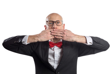 Slim bald elegant nerd in black suit with bow tie gesturing Speak No Evil. Isolated on white.