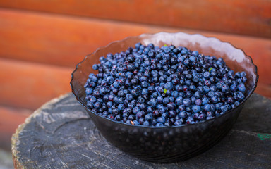 Freshly picked blueberries in wooden bowl. Juicy and fresh blueberries with green leaves on rustic table. Bilberry on wooden Background. Blueberry antioxidant. Concept for healthy eating and nutrition