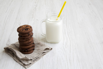 Chocolate cookies with milk on a white wooden background, side view.
