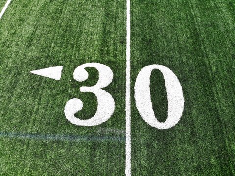 30 yard chalk mark on an green American football field taken from an aerial drone