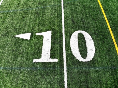 10 yard chalk mark on an green American football field taken from an aerial drone