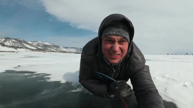 The extreme man is rolling down the snowy ice on the ice-boat. The ice-boat is tied to the car with a rope. The snow flies in the face. Russian crazy fun.