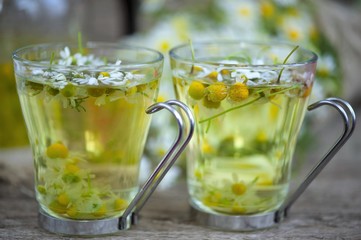 cup of chamomile tea with chamomile flowers on wooden planks 