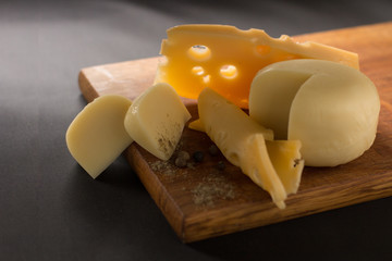 cheese of different sorts cut on a black background.